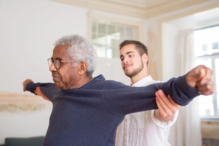 Fisioterapeuta acompanhando exercício de alongamento com paciente idoso