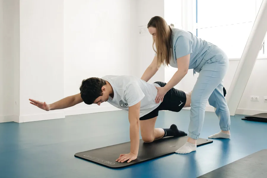 Fisioterapeuta conduzindo exercício de reabilitação em colchonete